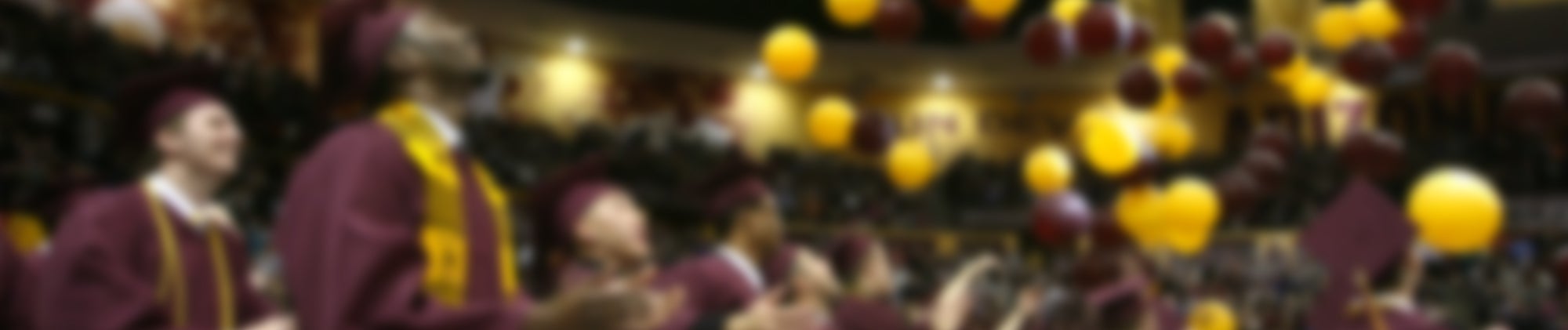 Graduates watching maroon and gold balloons drop from the ceiling